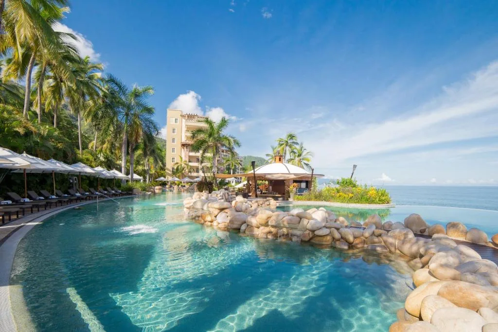Lagoon-style infinity pool lined with palms and cabanas